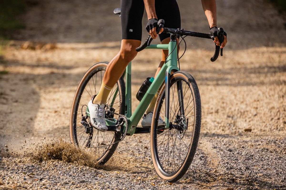 a riding skidding down a gravel road on a bianchi impulso pro