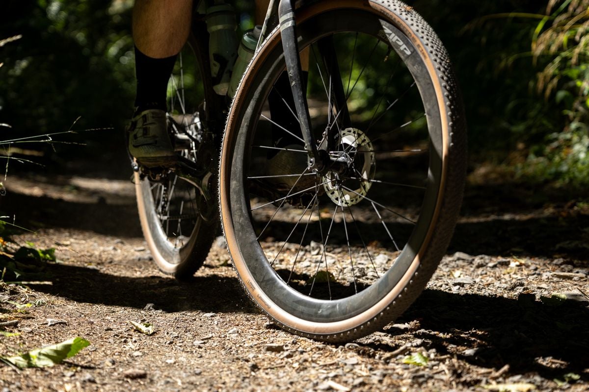 Cyclist riding on gravel road in the forest.