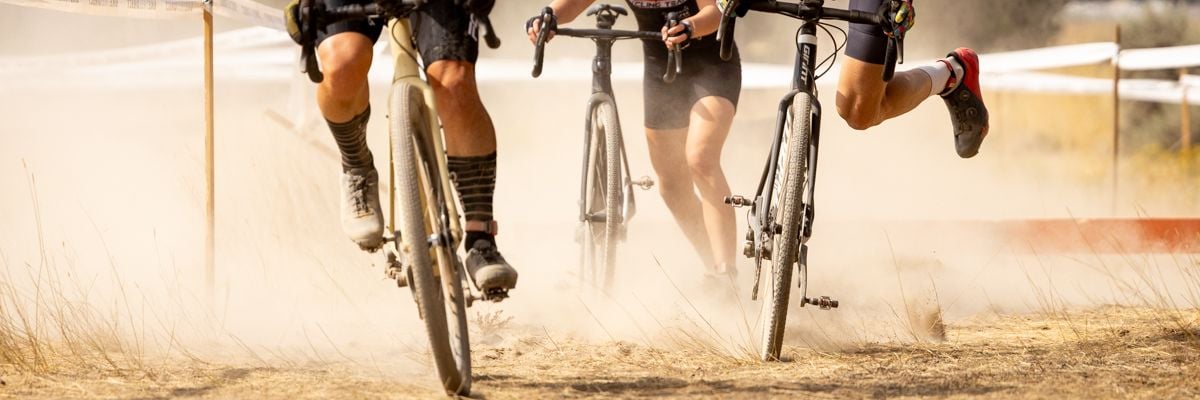 Cyclists remounting their bicycles on a sandy course