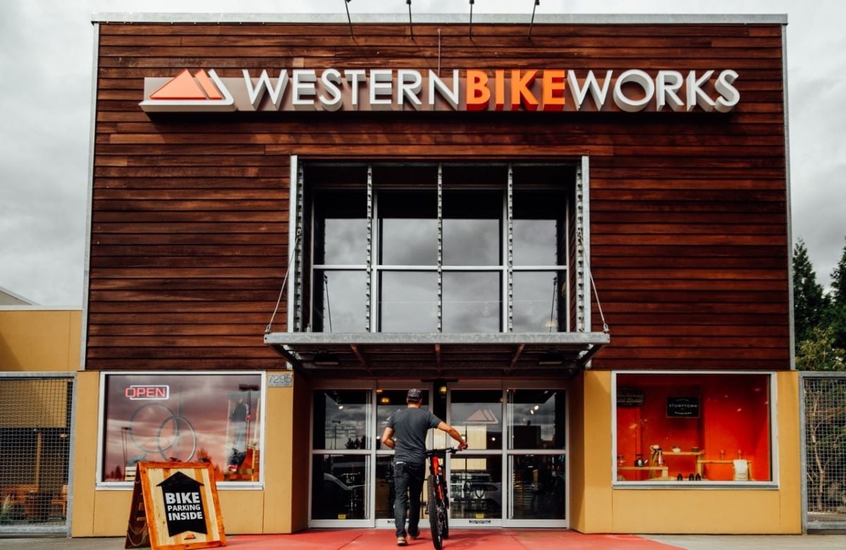 an exterior image of the old western bikeworks storefront in Tigard, Oregon, with a person walking a mountain bike through the front door
