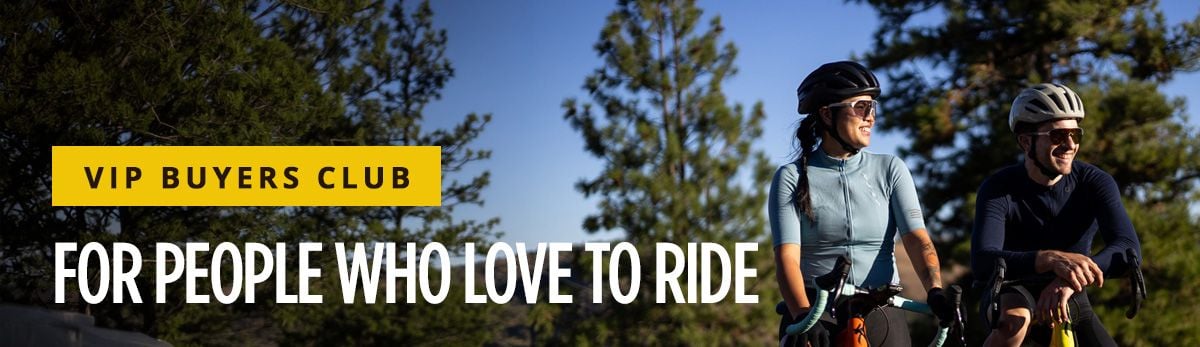 VIP Buyers Club banner, featuring two cyclists in late evening sun smiling in a forested setting
